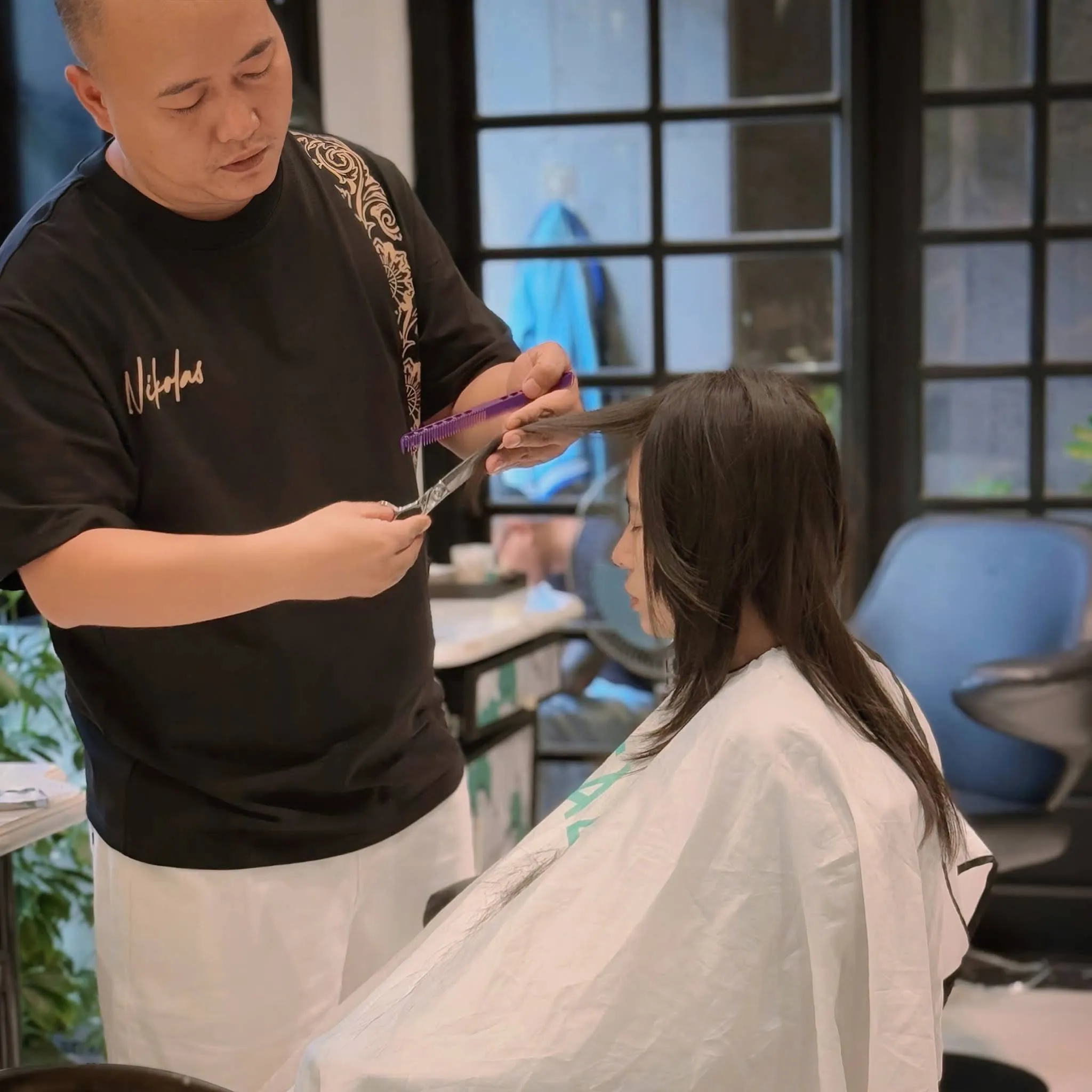 Stylist giving a precision scissor haircut at Nien Is New hair salon in Da Nang
